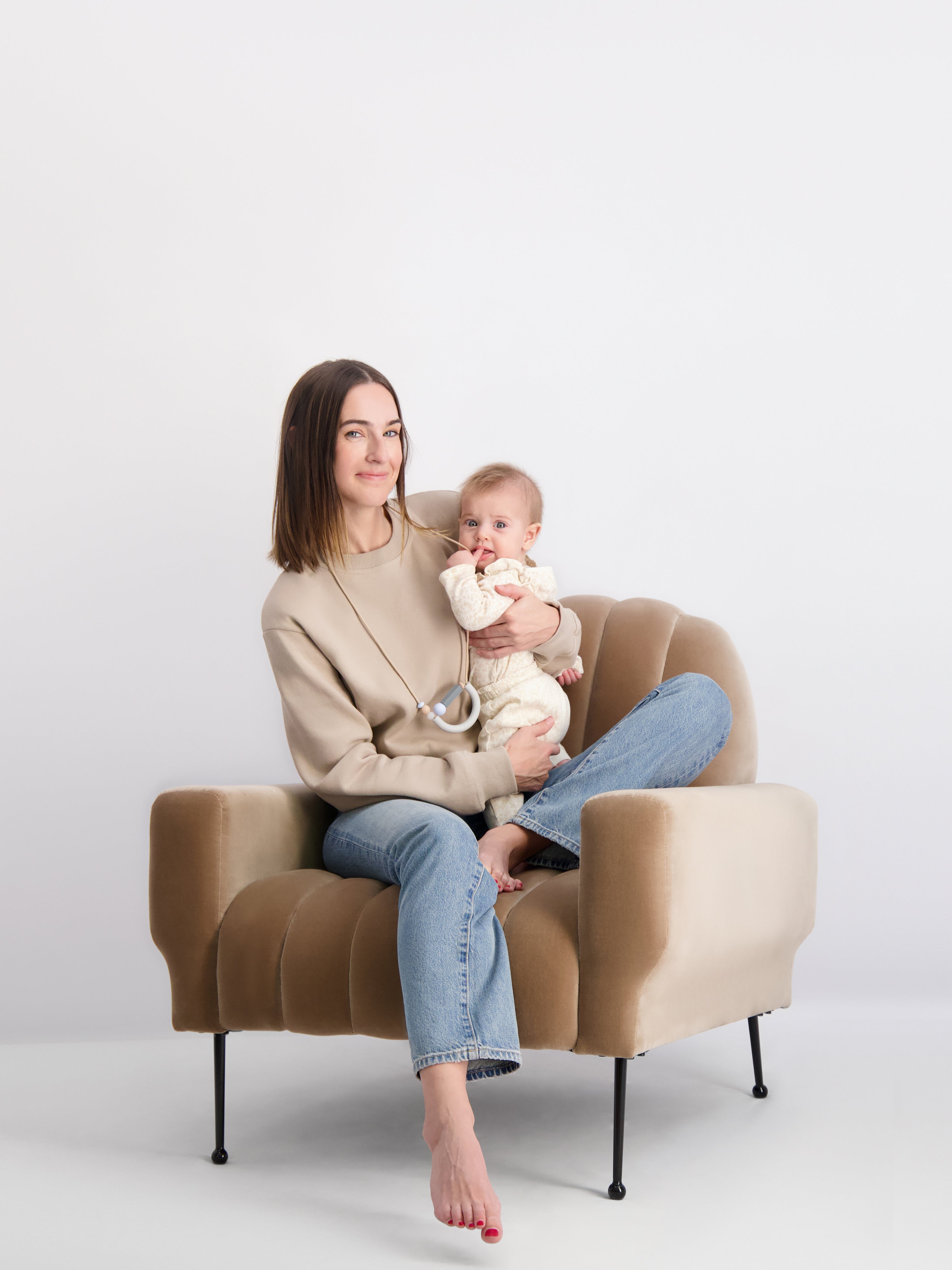 Mom wearing our Bloom Teething Necklace in the Moonstone colorway and her baby is interacting with it.